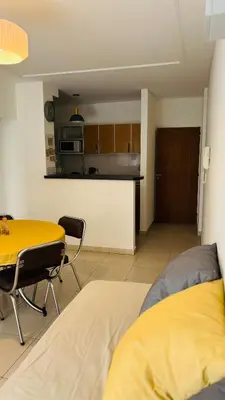 a living room with a table and a kitchen at Departamento centrico amoblado in Río Cuarto
