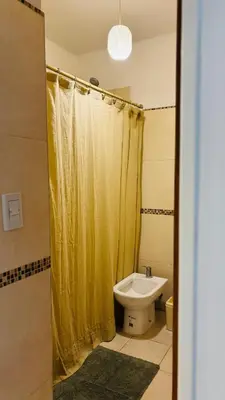 a bathroom with a yellow shower curtain and a toilet at Departamento centrico amoblado in Río Cuarto