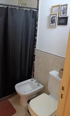 a bathroom with a toilet and a black shower curtain at HOUSING- Vistas a las sierras-Departamento temporario amoblado in Cordoba