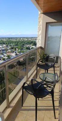 a balcony with two chairs and a view of a city at HOUSING- Vistas a las sierras-Departamento temporario amoblado in Cordoba