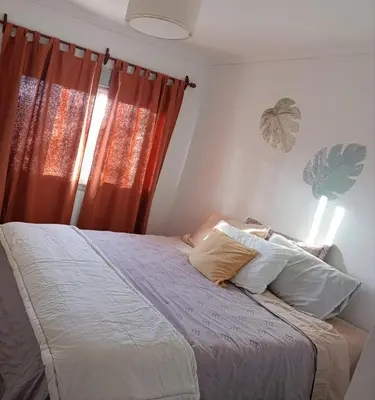 a bedroom with a bed and a window with orange curtains at HOUSING- Vistas a las sierras-Departamento temporario amoblado in Cordoba