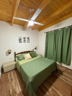 a bedroom with a green bed with a ceiling fan at Ideal para parejas en Anisacate in Villa Anizacate