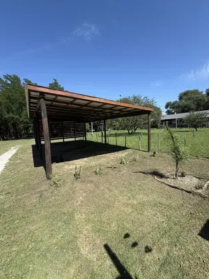 a wooden structure with a roof on a grass field at Ideal para parejas en Anisacate in Villa Anizacate