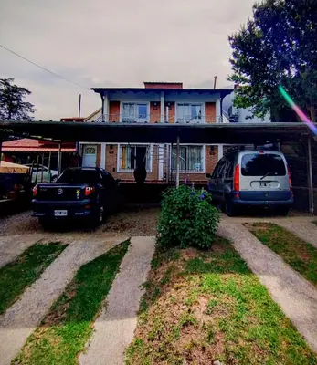 a house with two cars parked in front of it at Calamuchita Apart Dos Talas in Santa Rosa de Calamuchita
