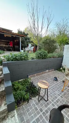 a patio with a table and a bench and a wall at Calamuchita Apart Dos Talas in Santa Rosa de Calamuchita