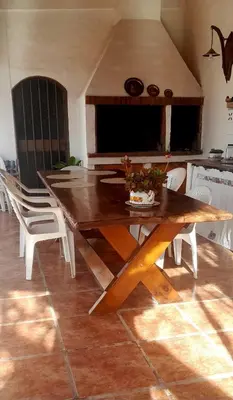 a wooden table in a kitchen with white chairs at En lo de Ana in Villa Dolores