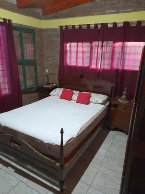 a bedroom with a bed with red curtains at La Quinta de Juan in Villa Anizacate