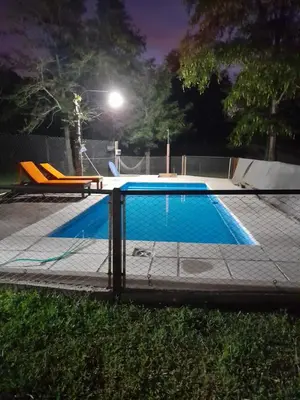 a swimming pool with a fence around it at night at La Quinta de Juan in Villa Anizacate