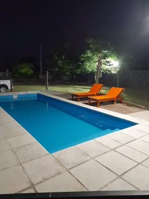 a swimming pool at night with two orange chairs at La Quinta de Juan in Villa Anizacate
