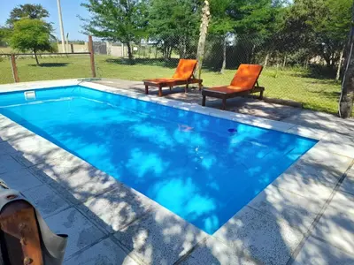 two chairs and a swimming pool with blue water at La Quinta de Juan in Villa Anizacate