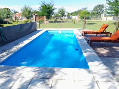 a swimming pool with two chairs and an orange chair at La Quinta de Juan in Villa Anizacate