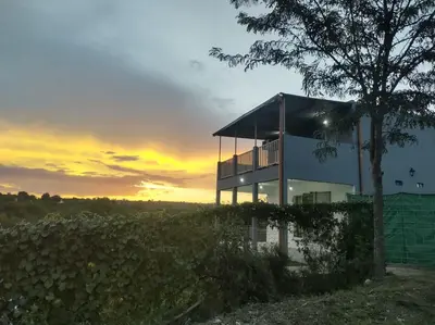 a house in a field with a sunset in the background at La Casita de Caeiro in Bialet Massé