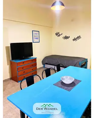 a room with a table and a tv and a bed at Casa Der Wandel in Villa General Belgrano