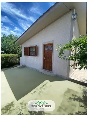 a small white house with a brown door at Casa Der Wandel in Villa General Belgrano