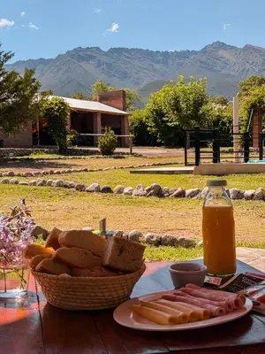 a table with a basket of bread and a bottle of juice at Cabañas Las Glicinas in Las Rabonas