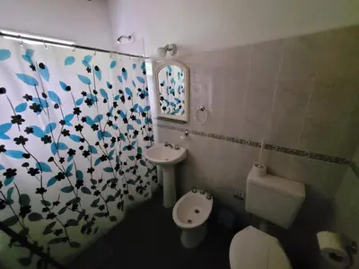 a bathroom with a toilet and a shower curtain at Cabañas Las Glicinas in Las Rabonas
