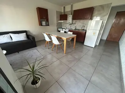 a kitchen and living room with a table and a couch at HERMOSO DEPARTAMENTO en COMPLEJO CERRADO in Estancia Vieja
