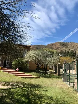 a house with a fence and a hill in the background at Finca - CASONA LAS MANSAS in Bialet Massé