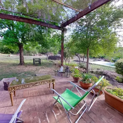 a patio with a table and chairs and trees at Casa con pileta en Cabalango - Sierras de Córdoba IG alquilervillacarlospaz in Cavalango