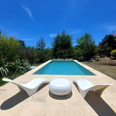 a swimming pool with two white chairs and a toilet at Casa con pileta en Cabalango - Sierras de Córdoba IG alquilervillacarlospaz in Cavalango
