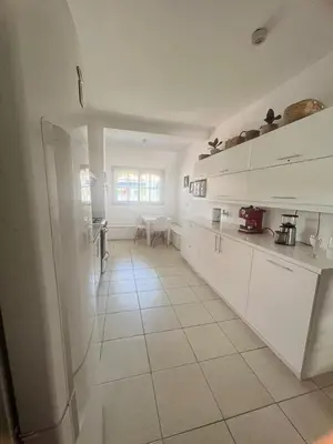 a kitchen with white cabinets and a white tile floor at casa santa rita in Villa Carlos Paz