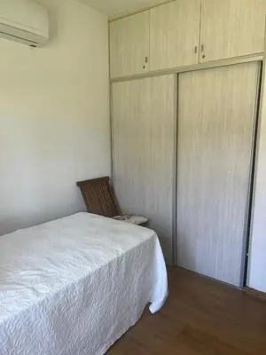 a bedroom with a white bed and a closet at casa santa rita in Villa Carlos Paz