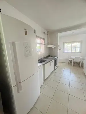 a white kitchen with a refrigerator and a table at casa santa rita in Villa Carlos Paz