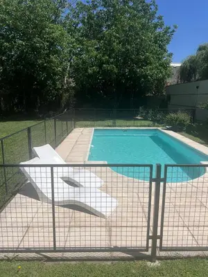 a swimming pool with a white chair next to a fence at casa santa rita in Villa Carlos Paz
