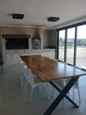a large wooden table in a kitchen with white chairs at Constantino Villa Carlos Paz departamento céntrico in Villa Carlos Paz