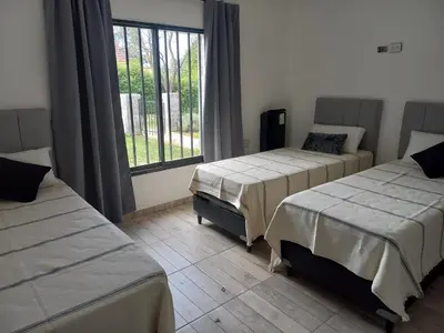a room with two beds and a window at La Casa del Mirador in Santa Rosa de Calamuchita