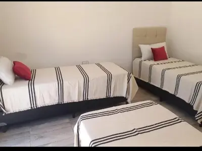 a room with two beds and two ottomans at La Casa del Mirador in Santa Rosa de Calamuchita