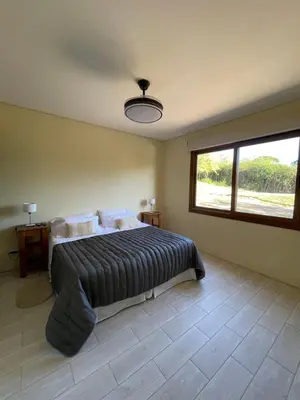 a bedroom with a bed and a large window at La Madruguera de Potrerillo in Alta Gracia