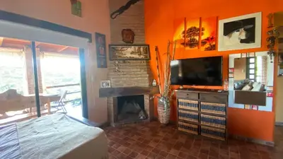 a living room with a fireplace and a television at Flor Serrana in Cavalango