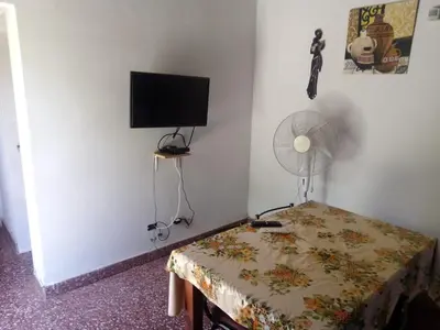 a room with a table and a fan and a television at Sierras y sol in Villa Cura Brochero