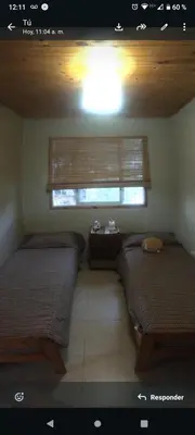 a room with two beds and a window with a window at Cabaña Flor Serrana in Tanti