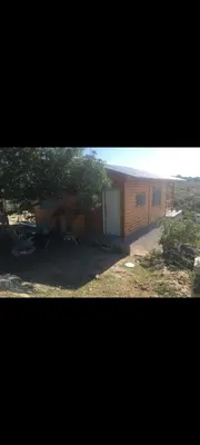 a house with a garage and a tree in front of it at Cabaña Flor Serrana in Tanti