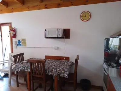 a dining room table with chairs and a microwave on the wall at La Nueva in Villa Ciudad Parque