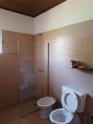 a bathroom with a toilet and a glass shower at La Nueva in Villa Ciudad Parque