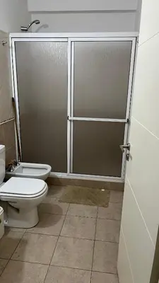 a bathroom with a toilet and a glass shower door at Departamento Orlando, zona centro in Villa Carlos Paz