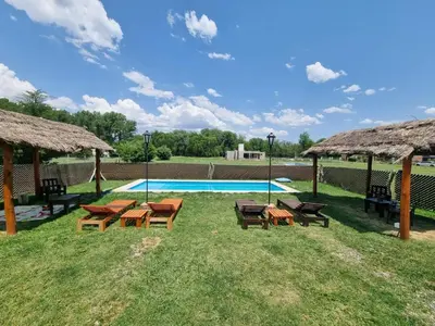 a swimming pool with picnic tables and chairs in the grass at Cabañas Nuevos Elefantes in Villa Cura Brochero