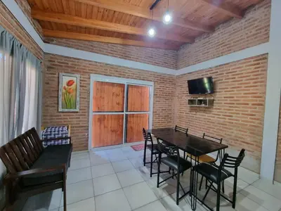 a dining room with a table and chairs and a brick wall at Cabañas Nuevos Elefantes in Villa Cura Brochero