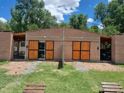 a brick building with wooden doors in a yard at Cabañas Nuevos Elefantes in Villa Cura Brochero