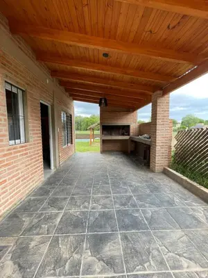 an outdoor patio with a wooden ceiling and a brick wall at Cabañas Nuevos Elefantes in Villa Cura Brochero