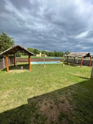 a field with two pavilions and a pool at Cabañas Nuevos Elefantes in Villa Cura Brochero