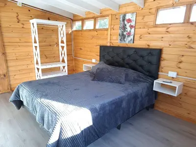 a bedroom with a bed in a wooden cabin at Depto Cabañero Lumai in Villa Ciudad Parque
