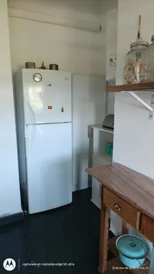 a kitchen with a white refrigerator and a table at Casa Amarilla in Santa Rosa de Calamuchita