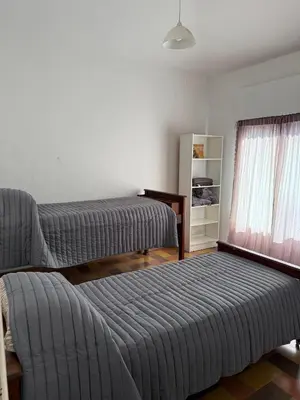 a bedroom with two beds and a chair and a window at Casa Amarilla in Santa Rosa de Calamuchita