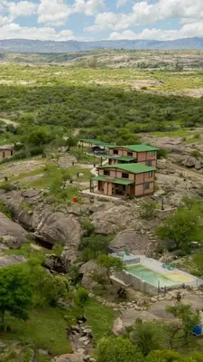a building on the side of a mountain with a pool at Kuntur Casas de Campo in Mina Clavero