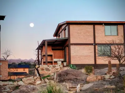 a house on a hill with the moon in the sky at Kuntur Casas de Campo in Mina Clavero