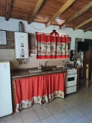 a kitchen with a sink and a red curtain at Cabañas del IntiCo in Arroyo de Los Patos